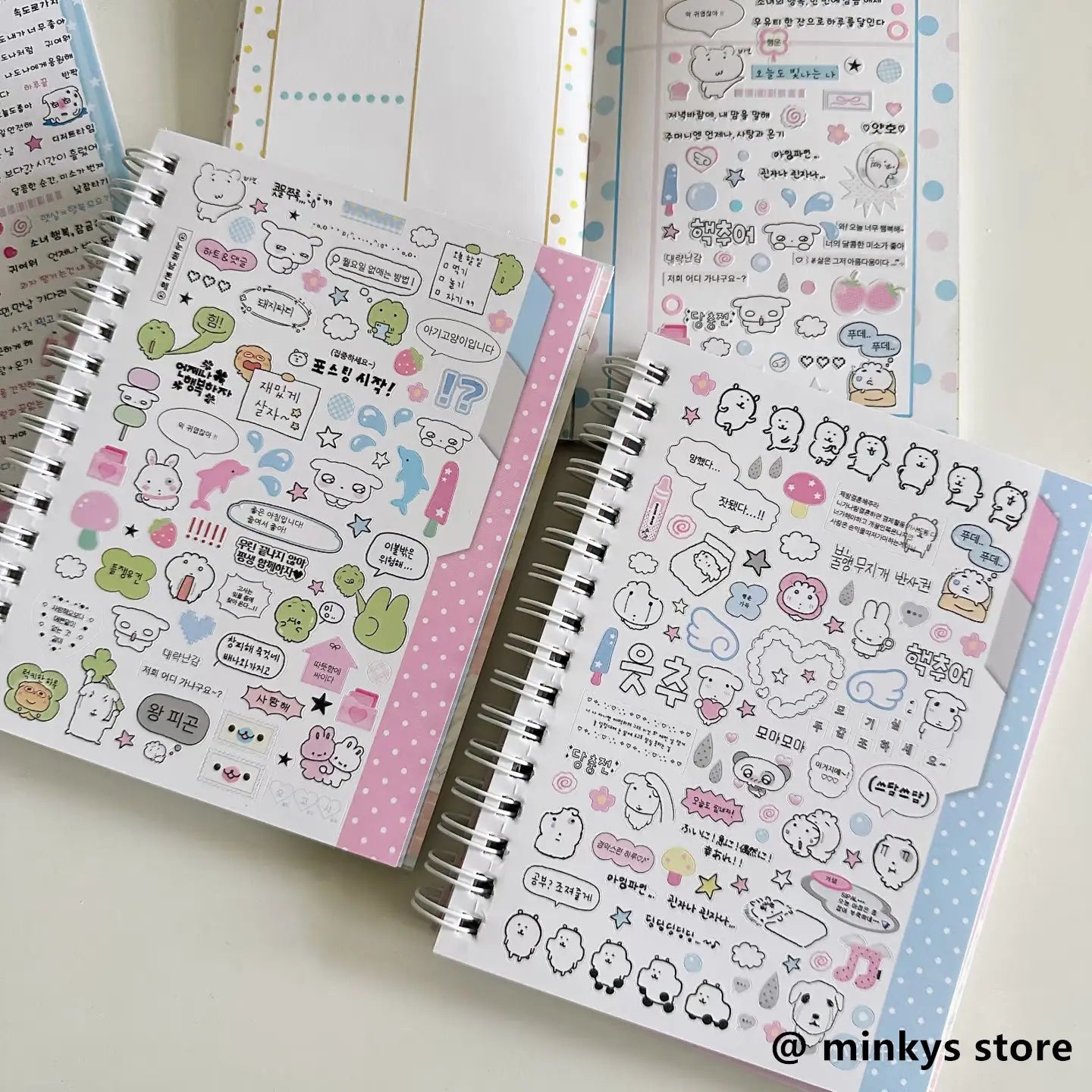 Ein rosa-weißes, gepunktetes spiralgebundenes Notizbuch, geschmückt mit farbenfrohen Cartoon-Stickerbögen aus der Kollektion „Kawaii Kpop sticker book spiral journal stationery“.
