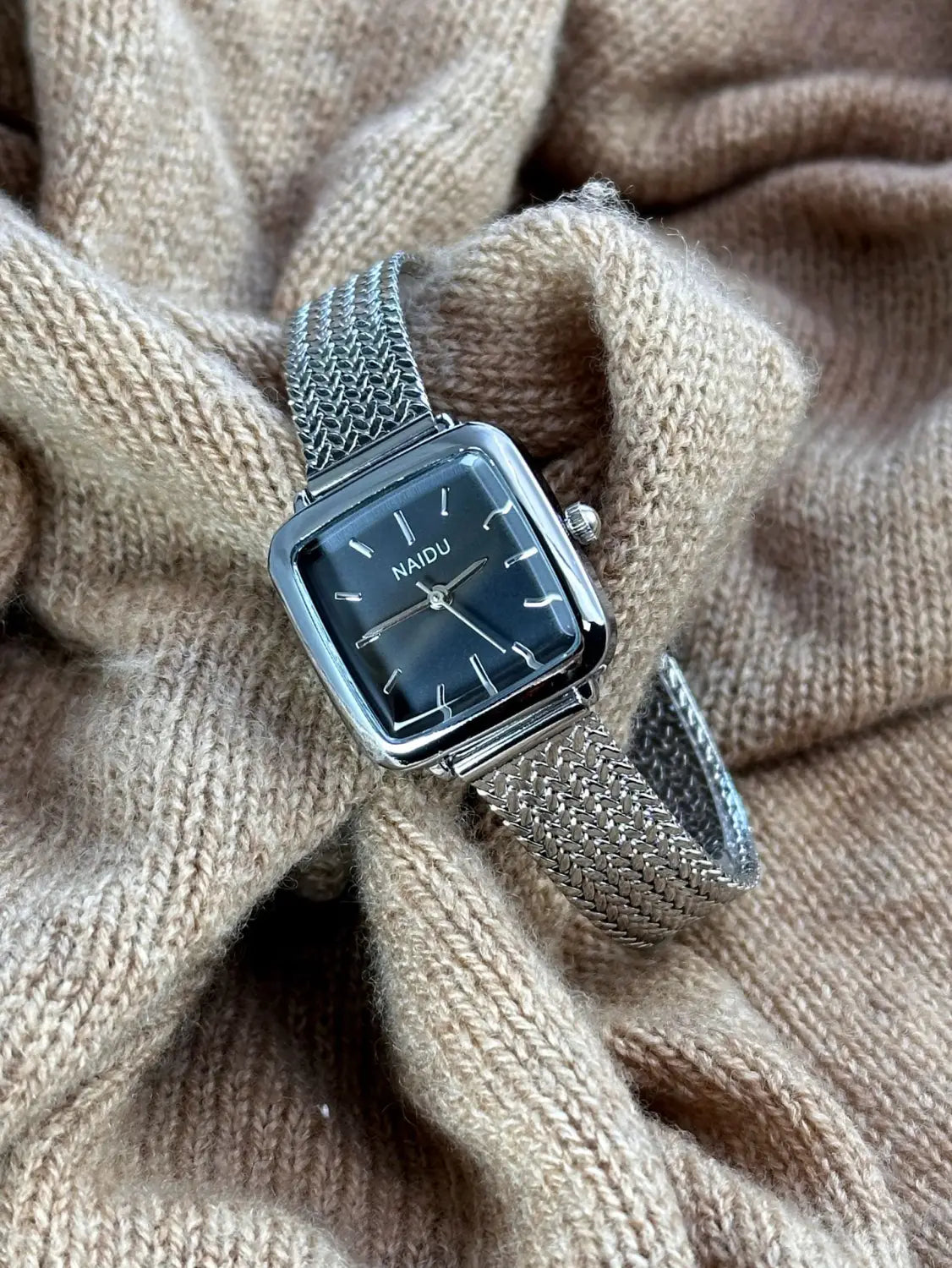Minimalist square quartz watch for women featuring a silver mesh bracelet with a square black dial and minimalist white hour markers.
