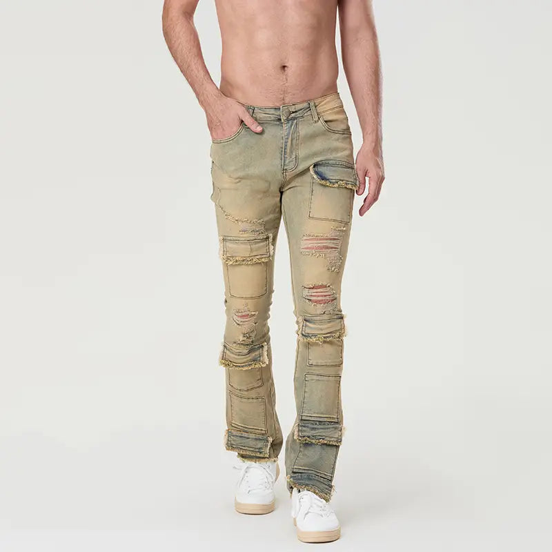 Des jeans empilés déchirés pour hommes, coupe slim, style streetwear, présentant un denim olive délavé, avec plusieurs patchs déchirés et des bords effilochés.