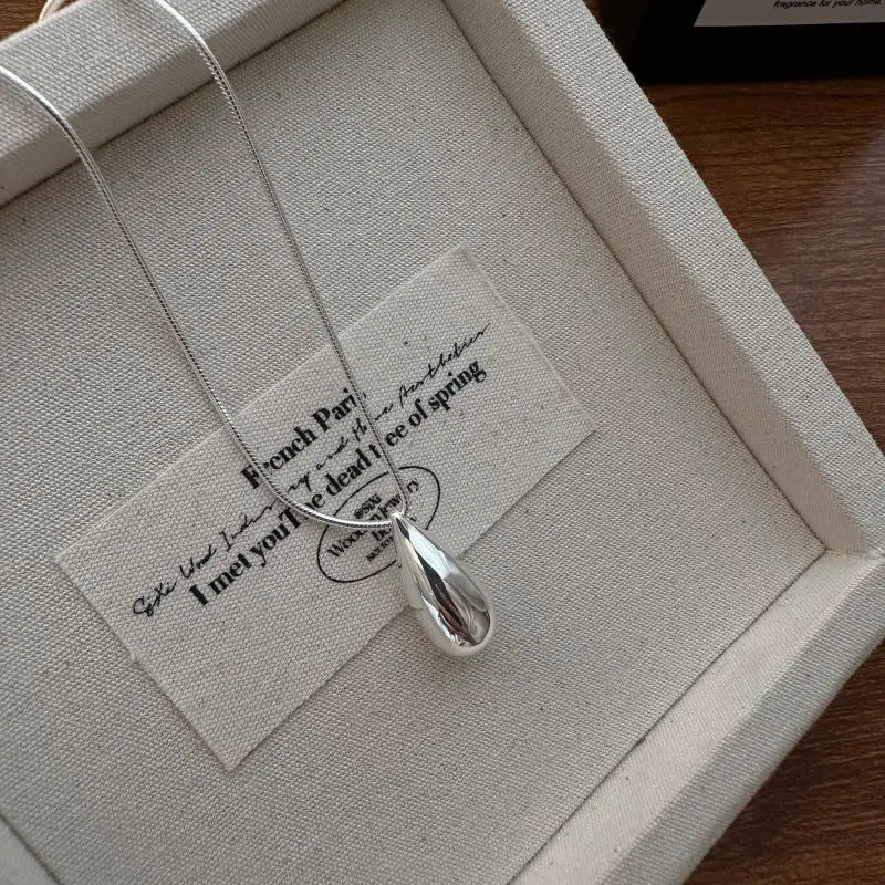Collier goutte de larmes en argent sterling épuré avec une finition polie et une chaînette délicate, dans un style de joaillerie fine.