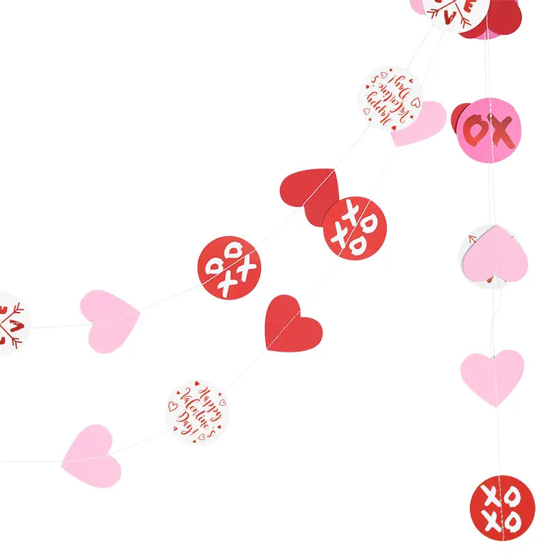 Guirnalda de corazones para San Valentín: pancarta con un diseño festivo de papel con corazones rojos y rosas, patrones circulares xoxo y círculos blancos impresos con «happy valentine’s day» en rojo en cursiva.