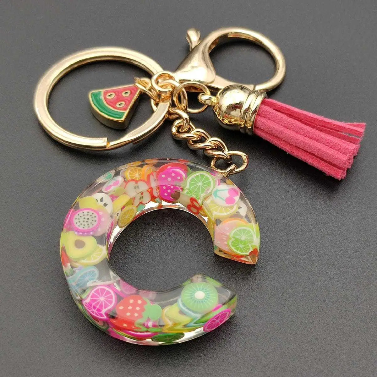 A translucent circular fruit letter resin keychain featuring a vibrant array of embedded fruit slices in clear resin.