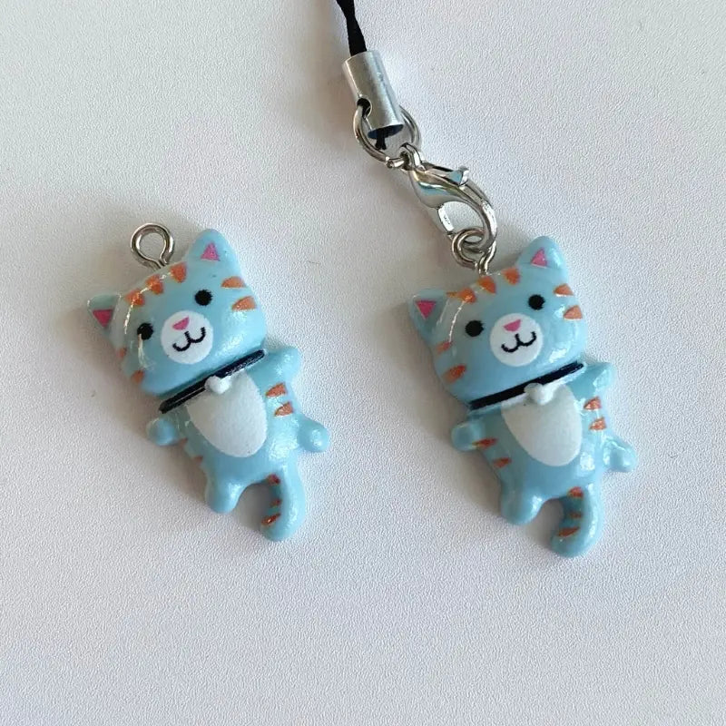 Cute cat phone charm strap featuring a light blue cat-shaped design with orange stripes and a white belly attached to a silver metal clasp.