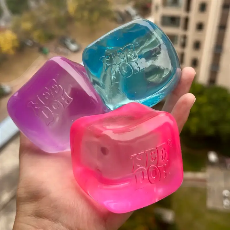three translucent cube-shaped needoh nice cube fidget toys in vibrant pink, purple, and blue hues viewed from above