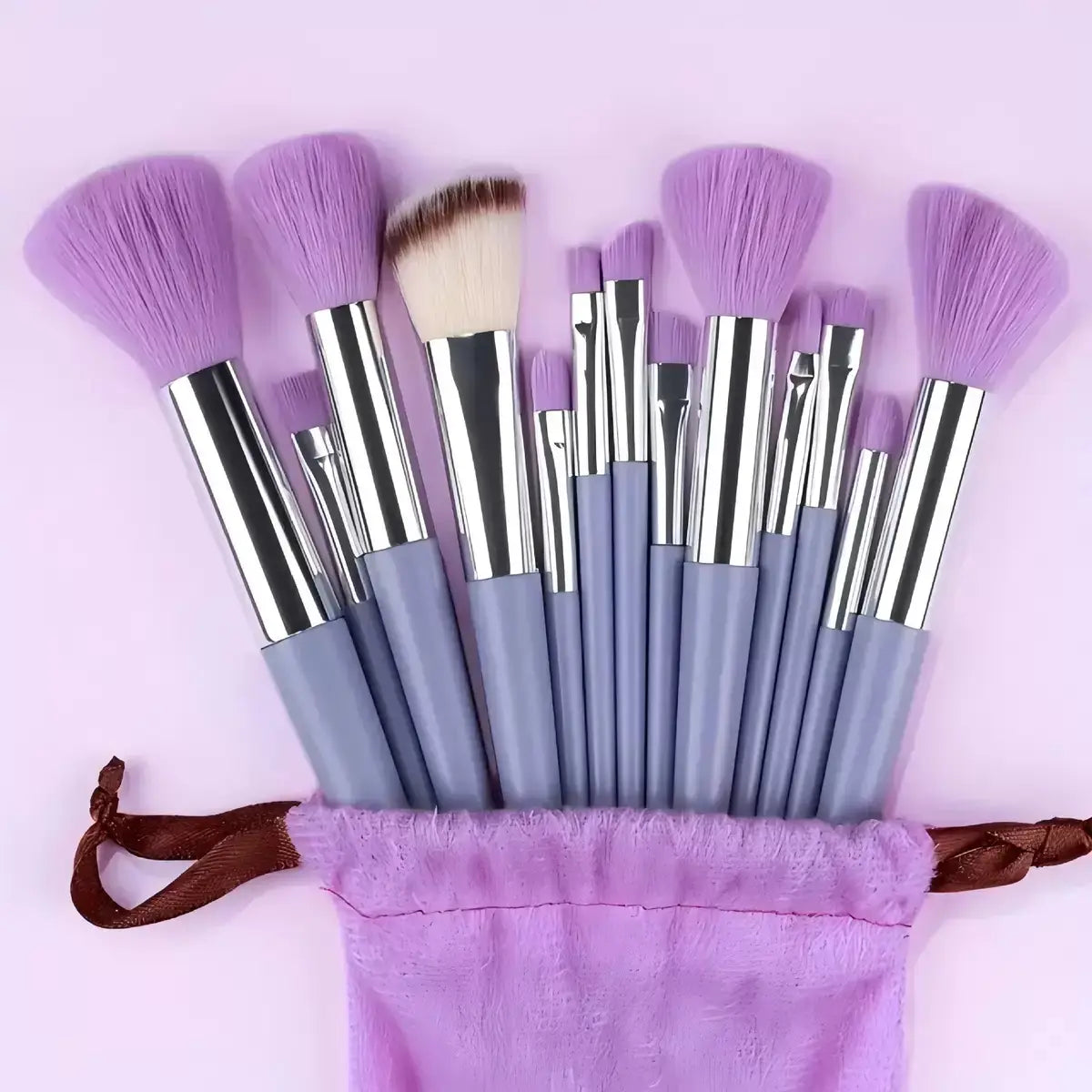 Un ensemble de 33 pièces de pinceaux et d’éponges de maquillage comprenant des pinceaux de couleur lavande, avec des poils en nylon comme matière des pinceaux, ainsi que des manches argentés et gris soigneusement disposés dans une pochette en velours pourpre.