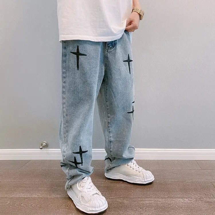 Pantalon cargo en jean à effet délavé clair avec broderie croisée noire, au design à jambes larges.