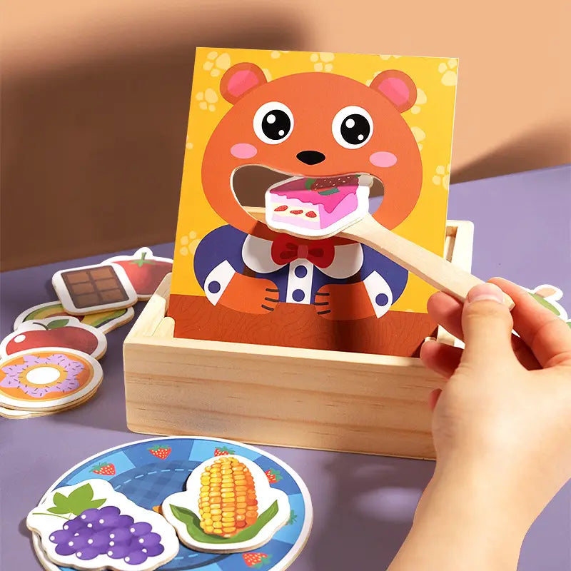Ein hölzernes Fütterspielzeug nach Montessori für Kleinkinder mit einem orangefarbenen Bärenthemen-Holzpuzzle, bei dem ein rosa gefrostetes Kuchenscheibenstück in den Mund des Bären eingesetzt wird.