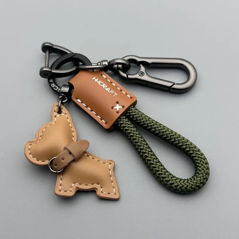 French Bulldog leather keychain featuring tan leather dog shape with olive green braided cord and black metal carabiners.