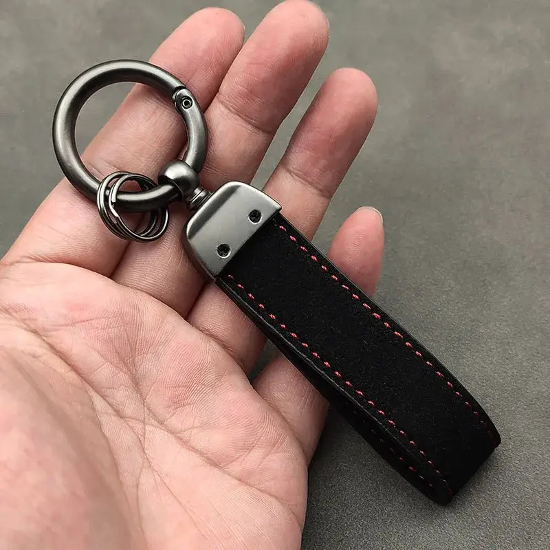 Schwarzer Lederschlüsselanhänger der GT Line mit rosafarbener Steppnaht und Metall-Karabinerhaken.