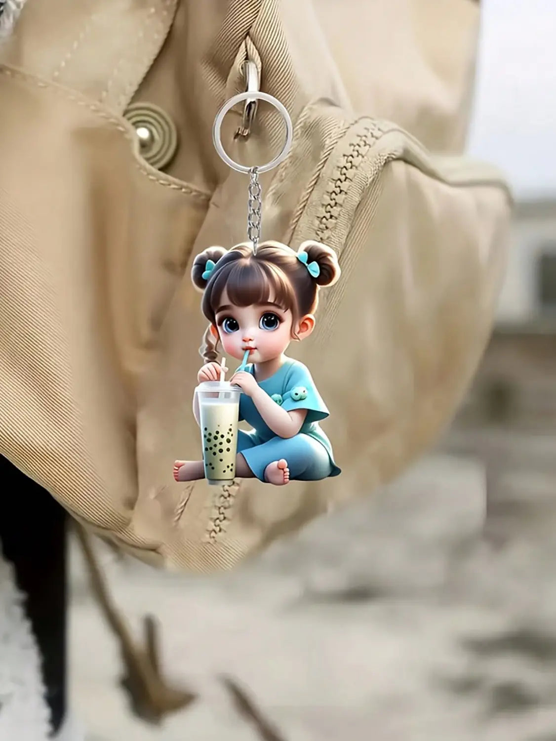 A charming blue acrylic girl keychain with pigtails and a matching outfit holding a bubble tea cup in a cute cartoon pendant design.