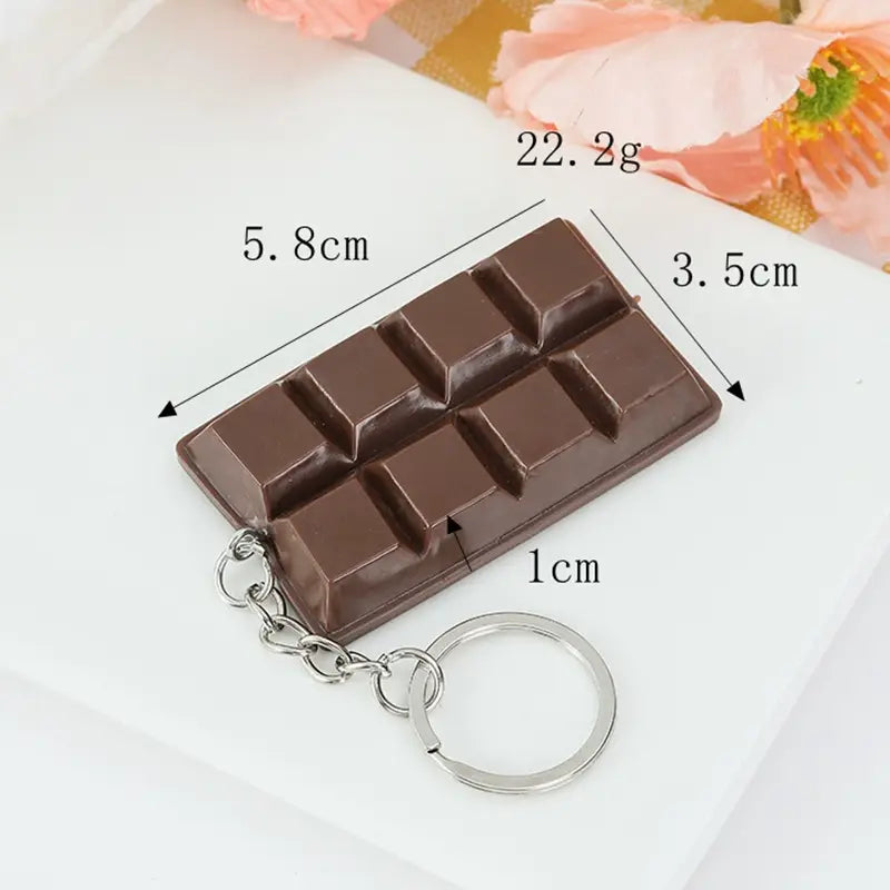 A miniature dark brown chocolate biscuit cartoon key chain bag pendant made of segmented candy with a silver metal ring and chain.