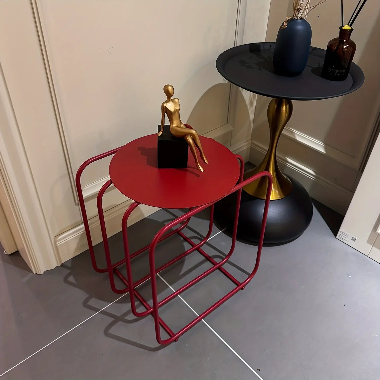 red metal side table with a circular top and curved frame designed as a minimalist storage magazine rack