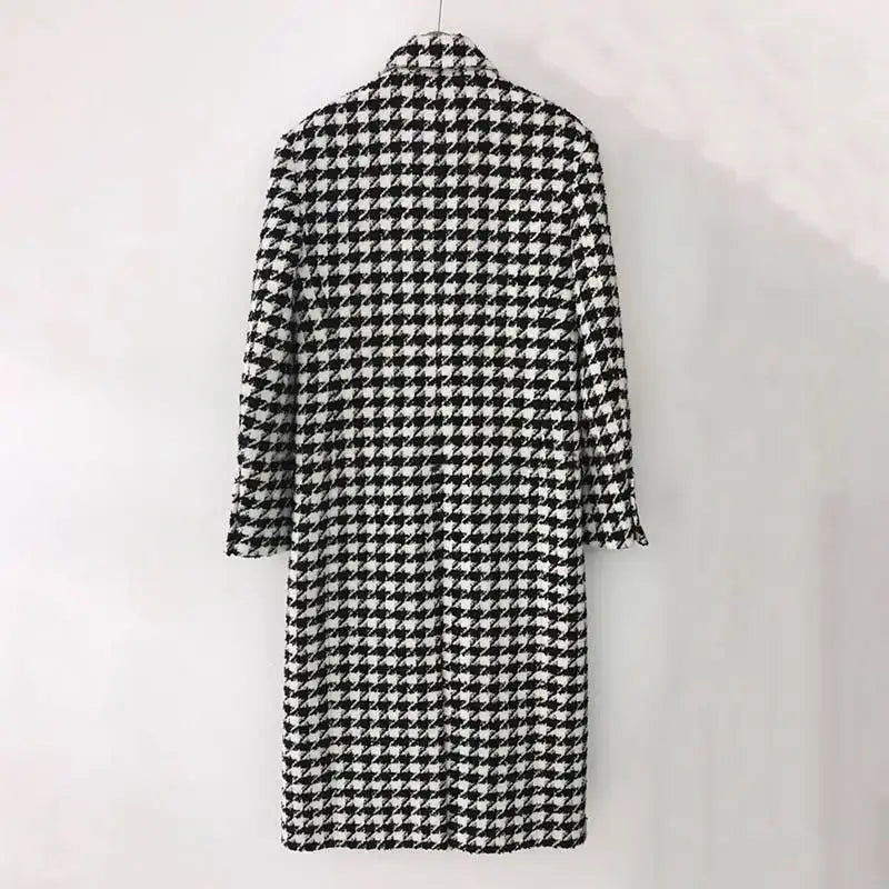 A black and white houndstooth wool double breasted coat with a classic collar and three quarter length sleeves.