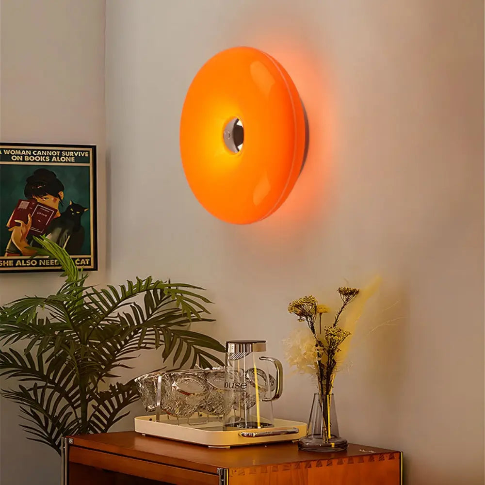 Luminaire mural tactile en acrylique orange éclatant, au design moderne circulaire et à luminosité réglable.