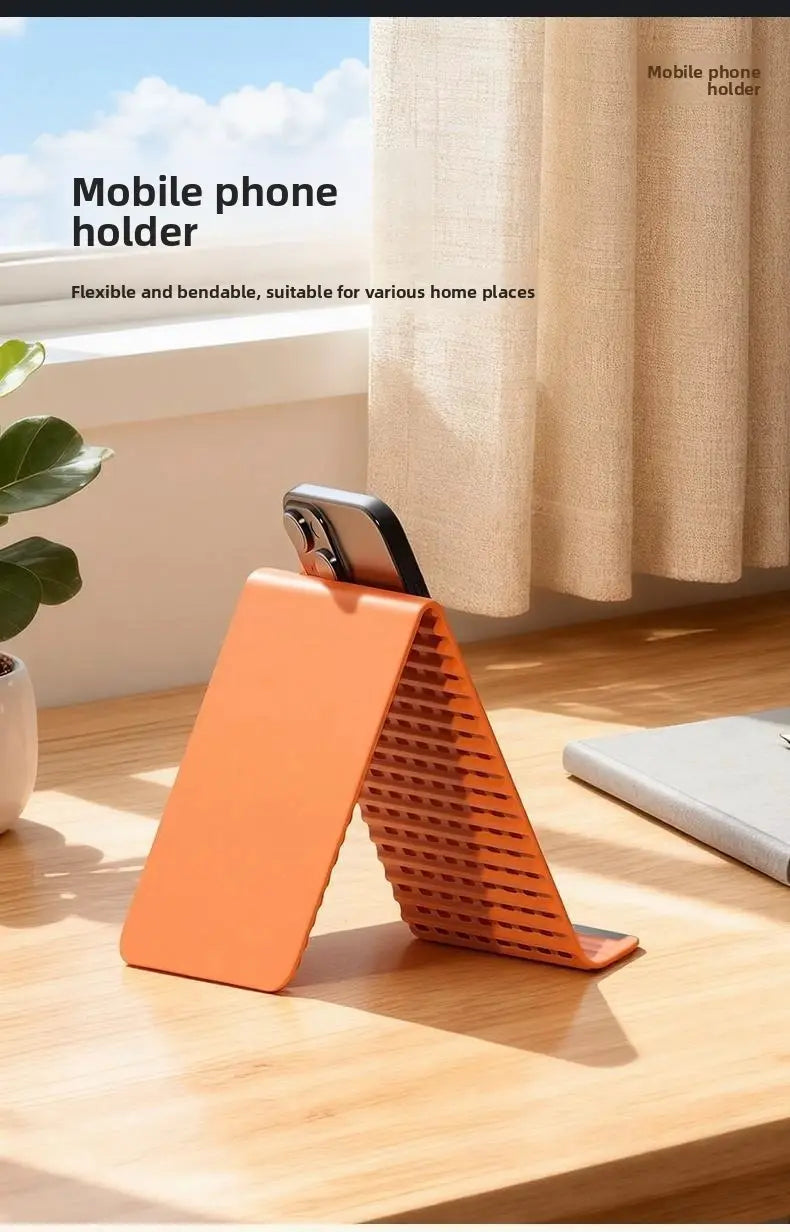 Soporte para teléfono plegable tipo perezoso de silicona flexible en color naranja, que muestra la superficie posterior con patrón de rejilla.