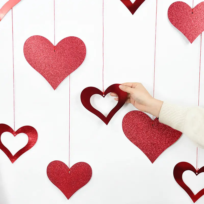 Guirnalda de corazones para San Valentín: pancarta con decoraciones colgantes en forma de corazón con brillo rojo, elaboradas con material luminoso, para decoración festiva.