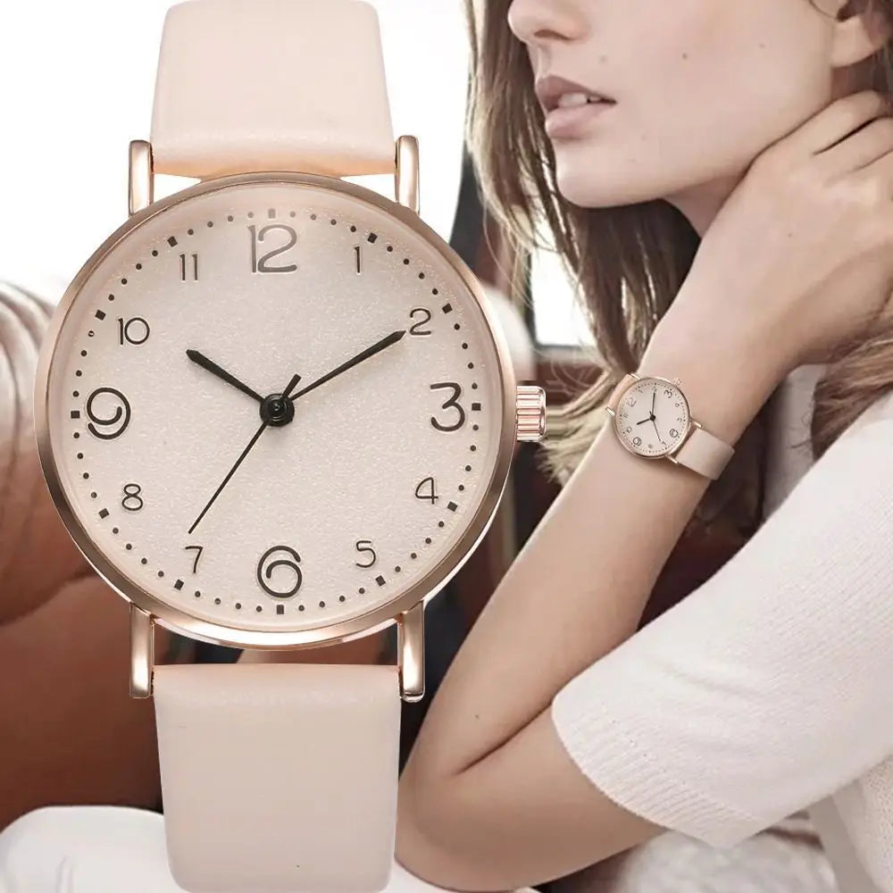 A delicate rose gold leather casual watch with a cream-colored strap and a minimalist dial featuring black arabic numerals.