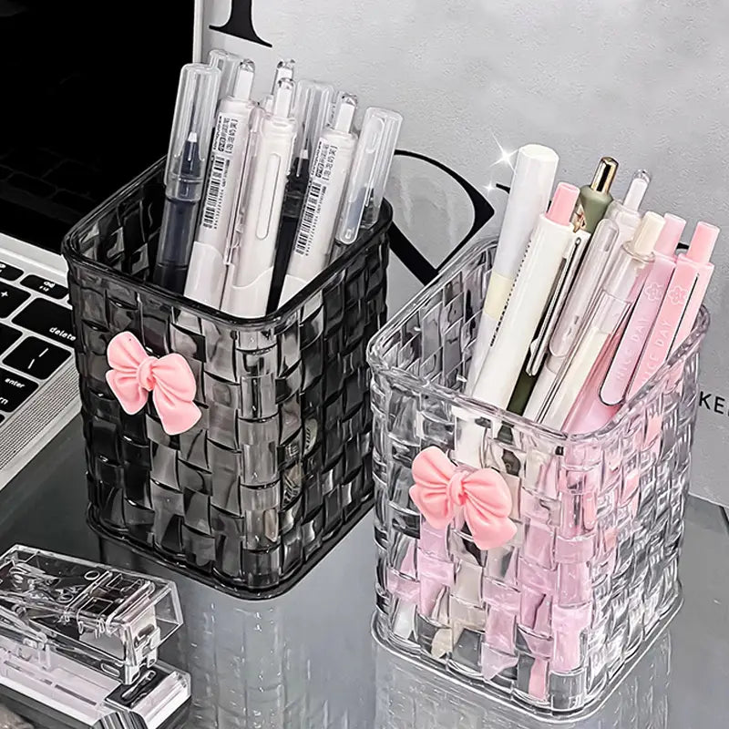 clear and black woven plastic bow pen holders each adorned with a pink bow designed as desktop storage organizers