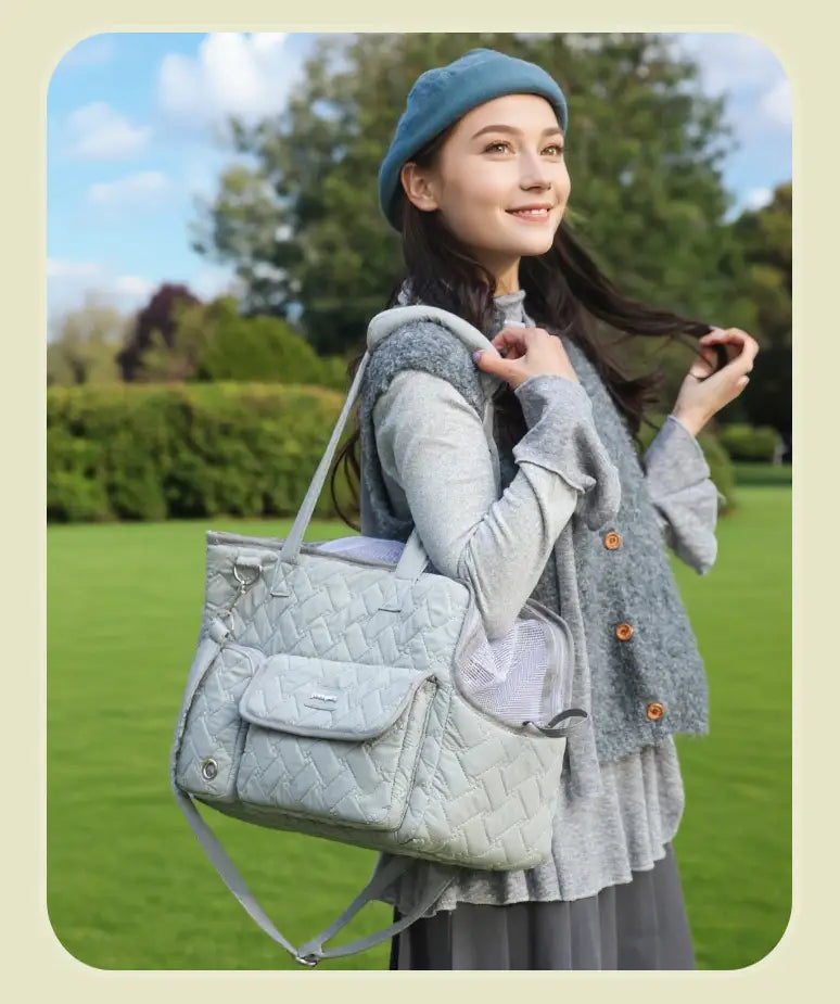 Bolsa transportín acolchada de color gris claro para mascotas, con bolsillo lateral de malla y correa de hombro ajustable, diseñada para gatos y perros pequeños.