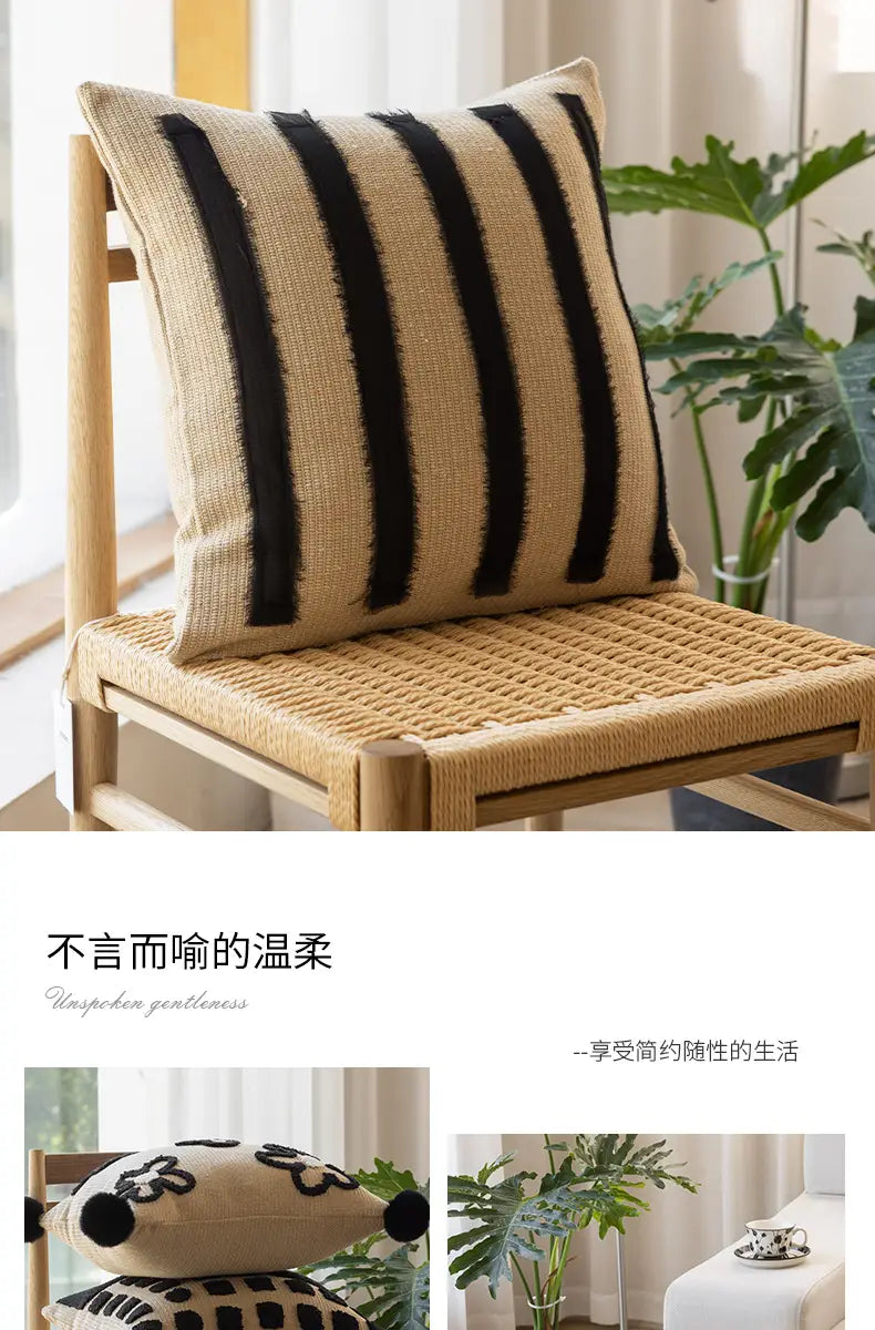 Housse de coussin bohème tissée beige et noire à rayures, avec une finition texturée en fibre naturelle, pour la décoration du salon.