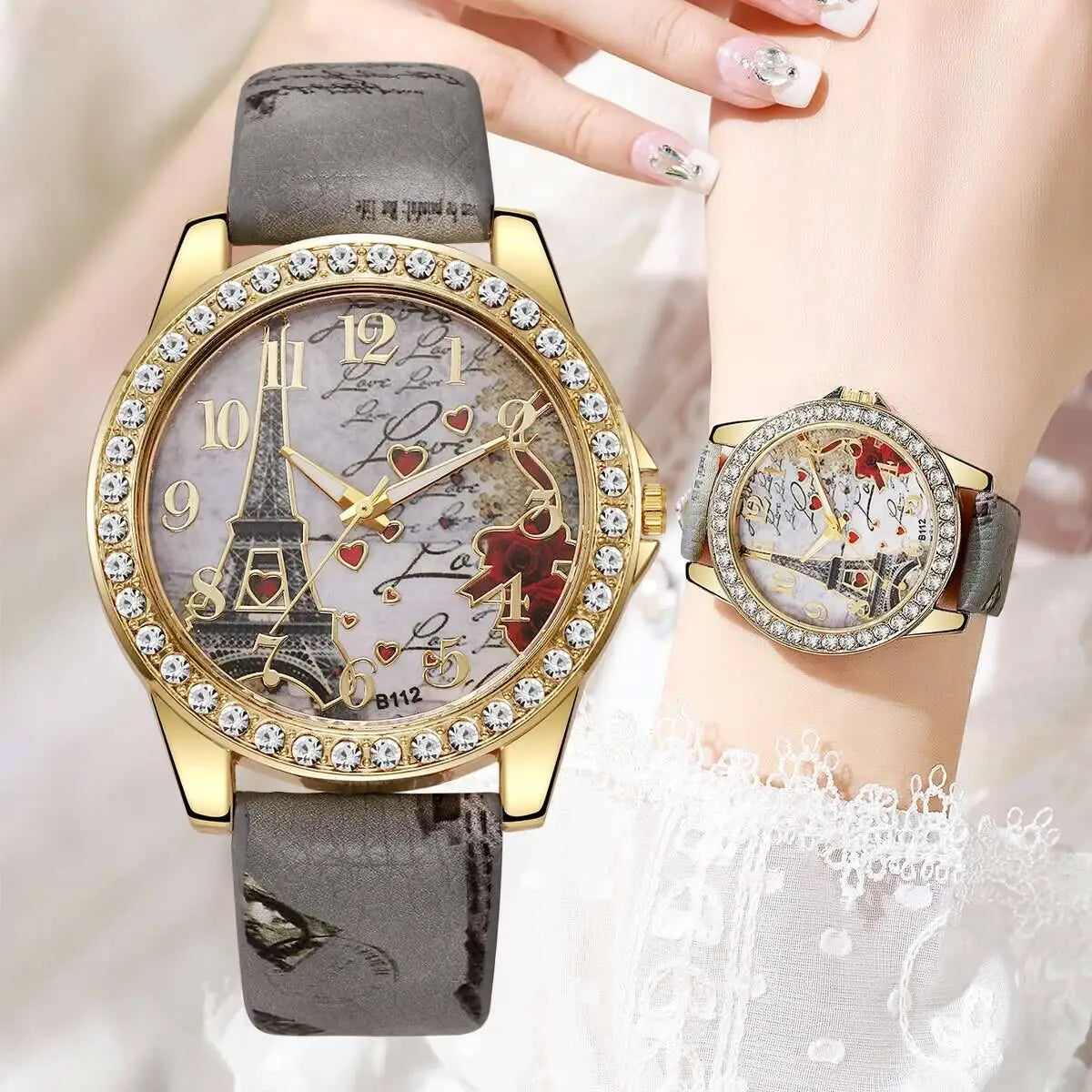 Gold-tone Eiffel Tower floral quartz women watch with a crystal-encrusted bezel and an Eiffel Tower design on the face adorned with hearts and cursive script.