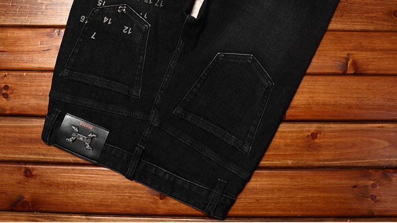 Mens slim fit printed black denim jeans shown from the back with subtle faded texture, reinforced stitching, and a branded patch on the back pocket.