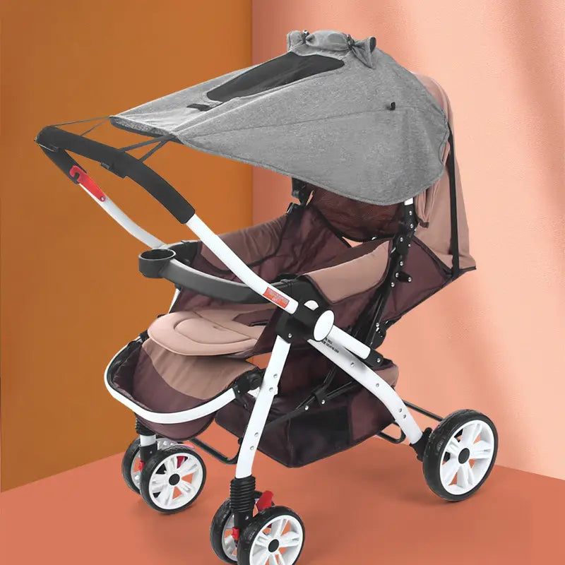 Ein moderner Universalkinderwagen mit grauem Sonnensegel aus UV-schutzierendem Stoff, weißem und schwarzem Rahmen sowie braunem gepolstertem Sitz mit passendem Aufbewahrungskorb.