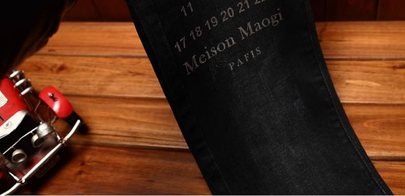 Black denim belt with meison maogi Paris embossed in silver lettering paired with mens slim fit printed black denim jeans.