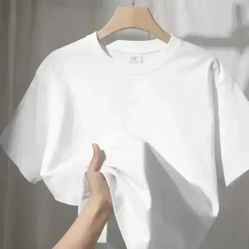 Una camiseta blanca impecable de manga corta y cuello redondo, confeccionada en algodón, colgada en una percha de madera, destacada en un listado de producto de una camiseta de algodón de cuello redondo color azul marino.