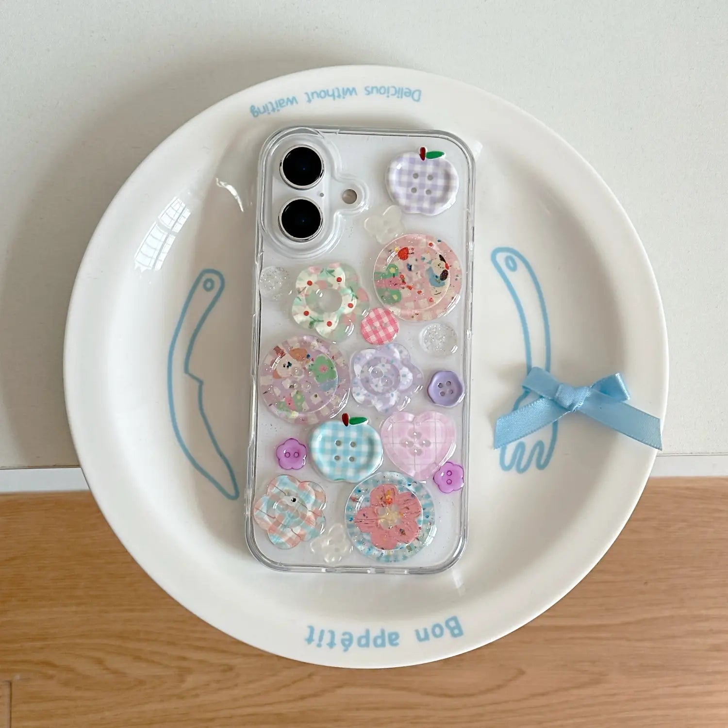 Funda transparente para teléfono para iPhone con adornos coloridos y translúcidos tipo botón en tonos pastel de rosa, azul y morado, mostrada desde la parte posterior