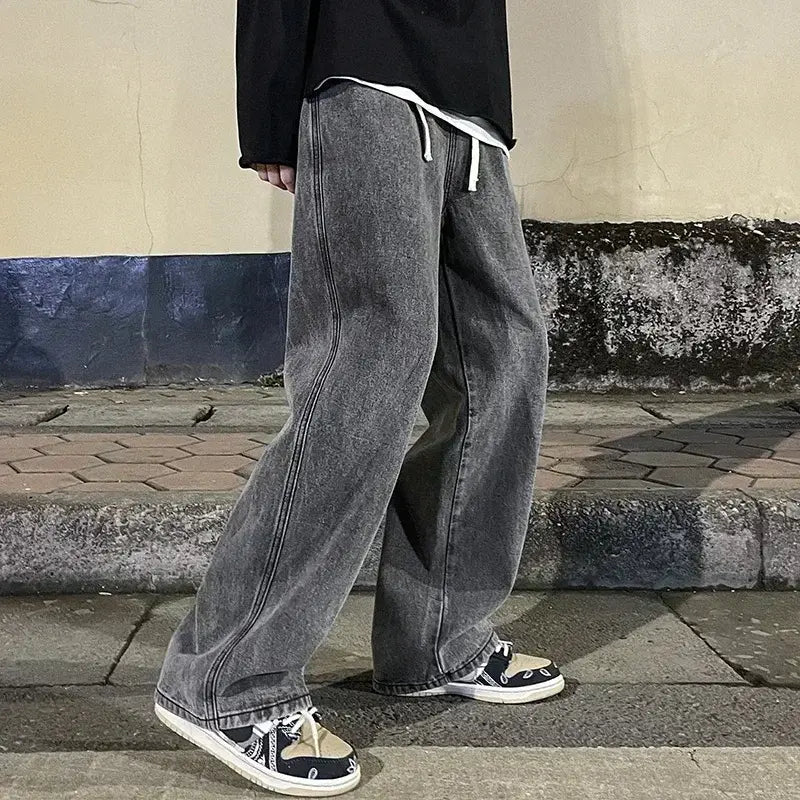 Pantalons en denim gris à jambes larges pour hommes, avec des cordons de serrage blancs et une silhouette décontractée à jambe droite, dans un style streetwear coréen.