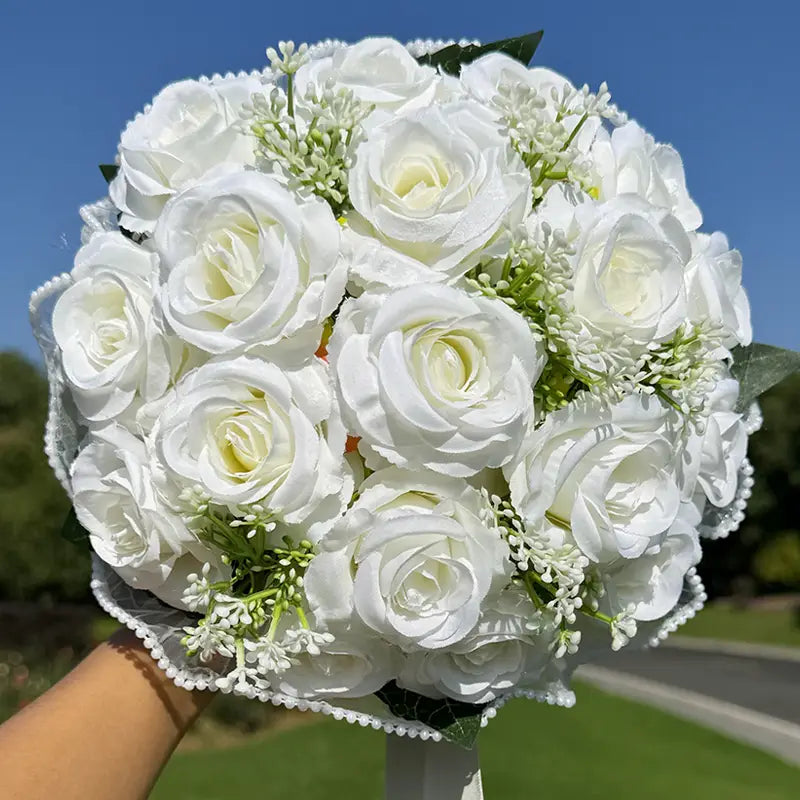 White silk rose wedding bouquet featuring white artificial roses with delicate lace wrapping and pearl-like trim.