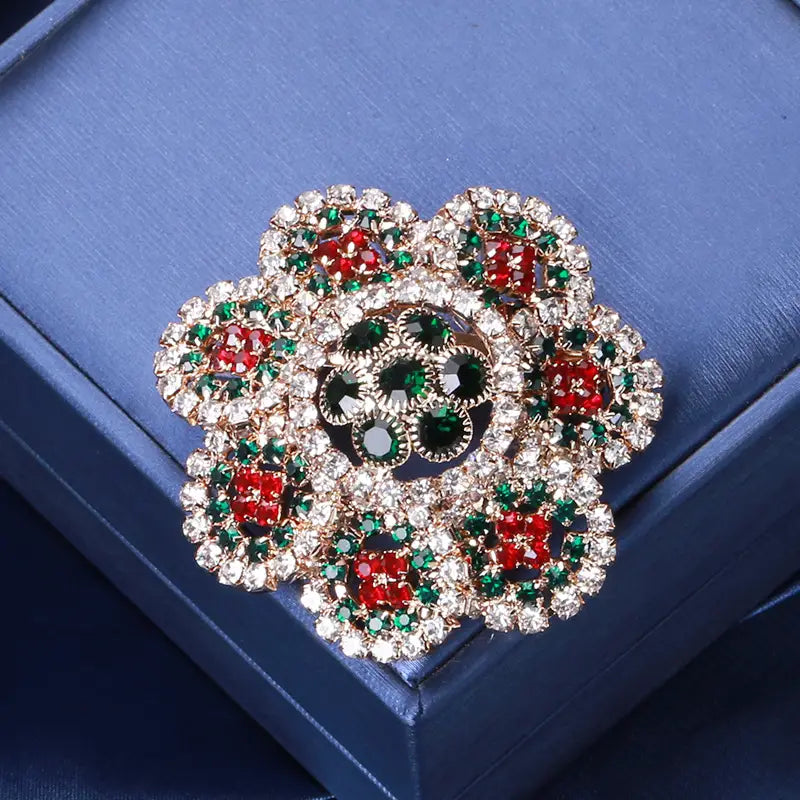 ローズゴールドトーンの金属ベースを備え、赤色および緑色のラインストーンの花をきらめかせた、ヴィンテージ宮殿風ジュエリーのスタイルのクリスタル・タッセル・ブローチ。