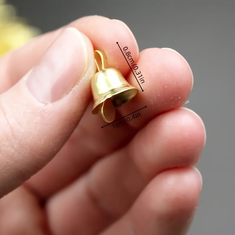 Une petite clochette de traîneau en métal doré, avec une finition métallique brillante et un sommet bouclé pour l’attache, faisant partie d’un ensemble de 20 pièces.
