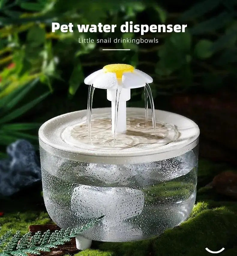 Clear glass cat water fountain with a white and yellow daisy-shaped flower top serving as a USB pet water dispenser.