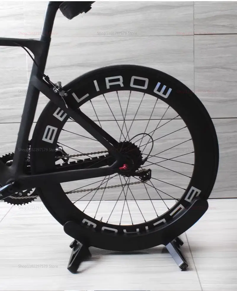 Roue de vélo en fibre de carbone noire portant la marque belirow en lettres blanches, fixée à un support de stationnement pour vélo réglable et à un rack de rangement.
