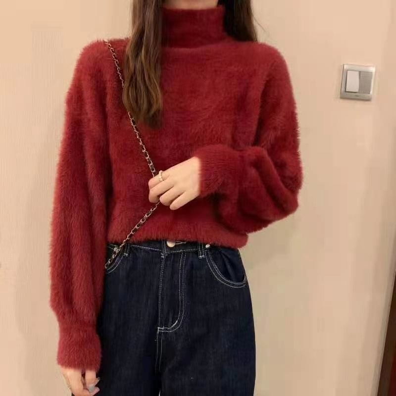A plush deep red fuzzy turtleneck sweater for women with long sleeves made of warm knit material ideal for winter wear.