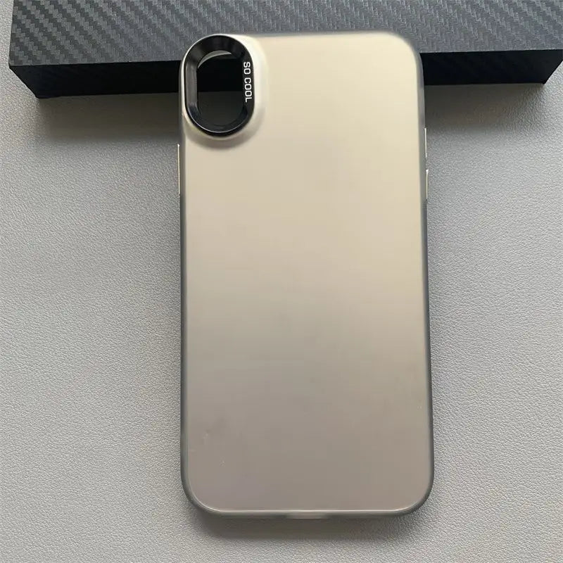 Un smartphone élégant en argent métallique, au design minimaliste, avec un accessoire circulaire noir pour lentille de caméra portant la mention « so cool », présenté depuis le côté arrière et mettant en évidence la coque pour téléphone iPhone en dégradé de couleurs mats.