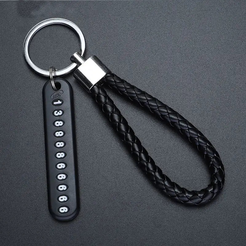 Black braided leather anti-lost stainless steel car key ring pendant with a silver metal ring and a black rectangular tag displaying white numbers.