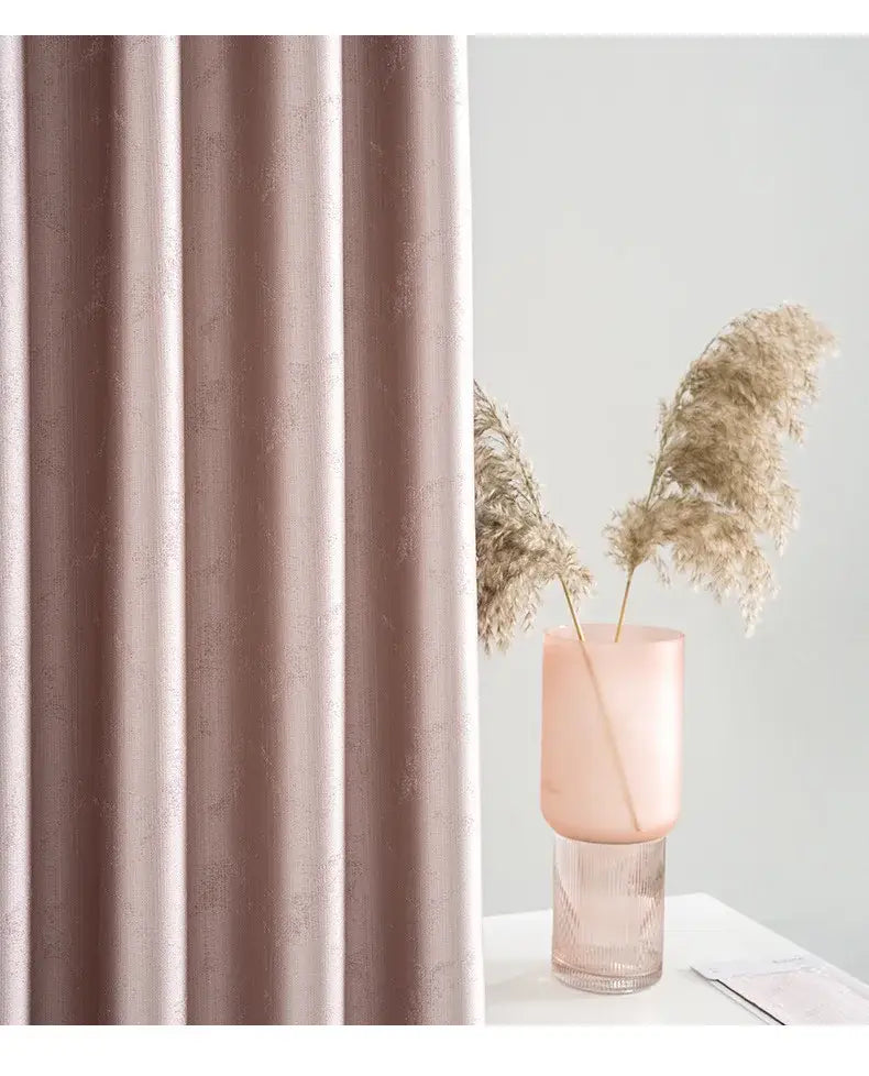 A soft blush pink textured living room curtain with subtle vertical pleats and a delicate metallic leaf pattern designed as custom blackout drapes para la sala.