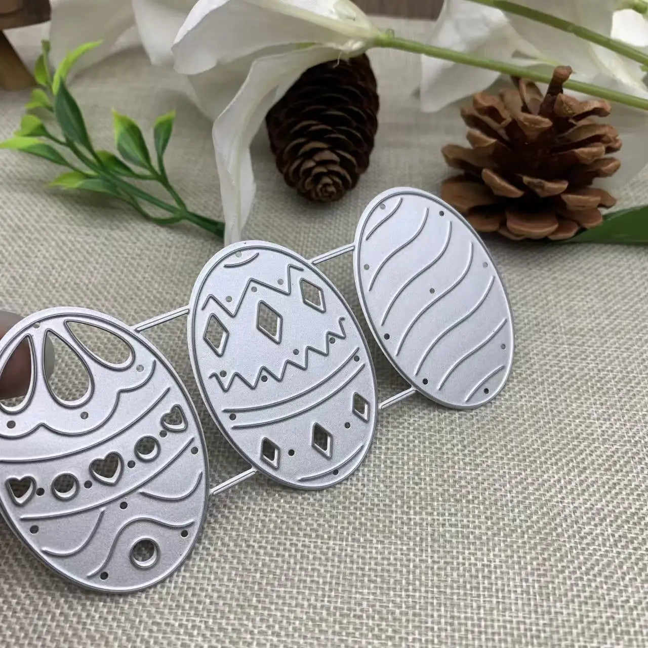 Set of three silver-toned metal easter egg-shaped die-cutters with intricate patterns and decorative cutouts for card making.