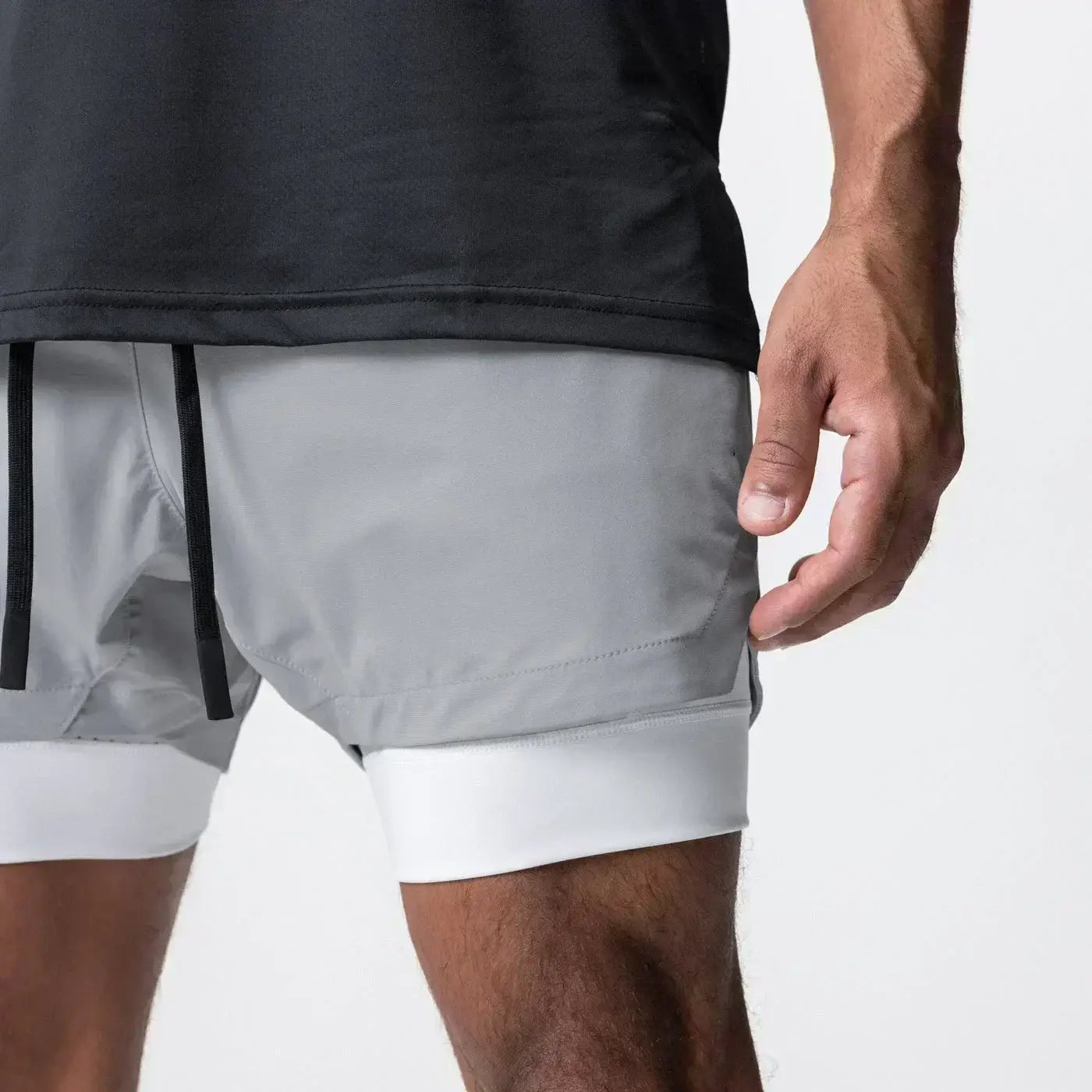 Hombres, pantalones cortos de entrenamiento atléticos grises 2 en 1 para gimnasio con capa interior blanca, cintura elástica, cordones negros y trabilla para la toalla para mayor comodidad.