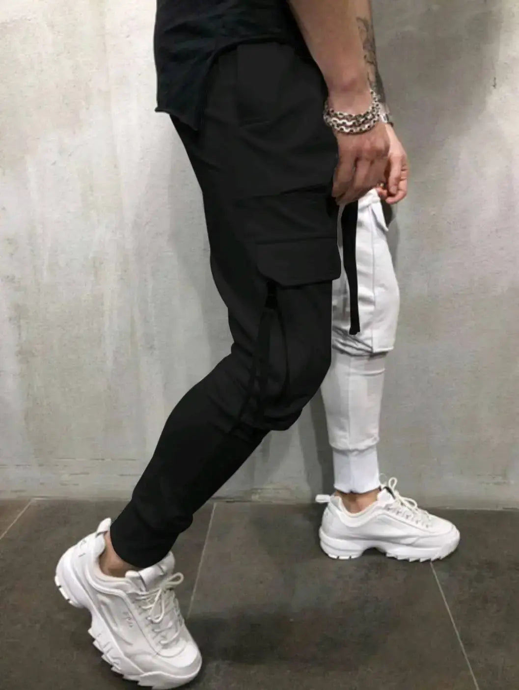 Zapatillas blancas de suela robusta con cordones gruesos y parte superior texturizada, combinadas con pantalones cargo tipo jogger de hip hop con bloques de color.