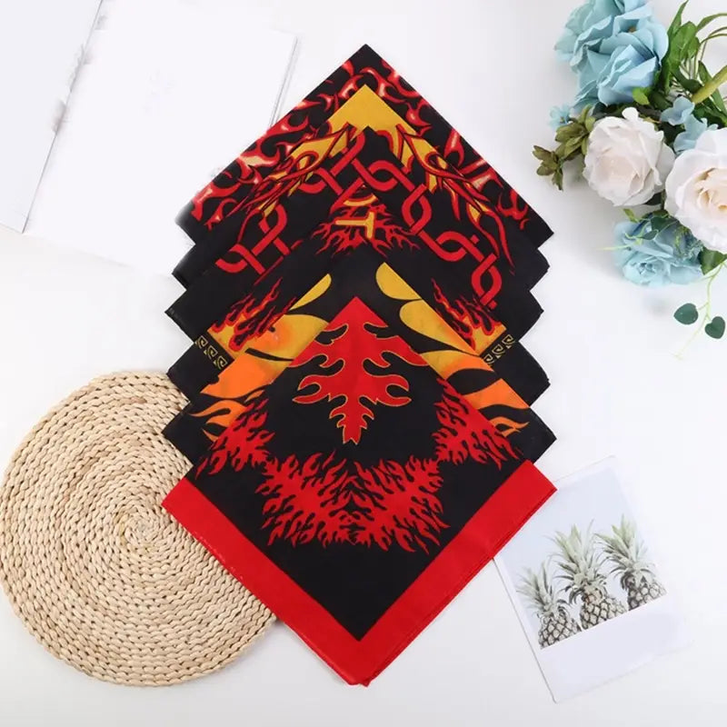 A stack of black flame pattern bandana head scarves with bold red and yellow flame designs and a solid red border.