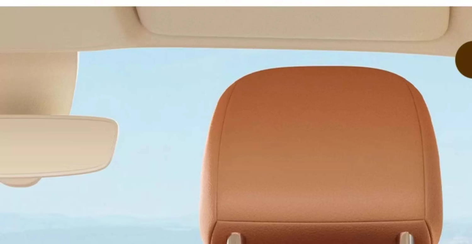 tan leather car headrest with smooth rounded contours and stitched edges shown on the back side of a car seat organizer animal alphabet storage pocket.