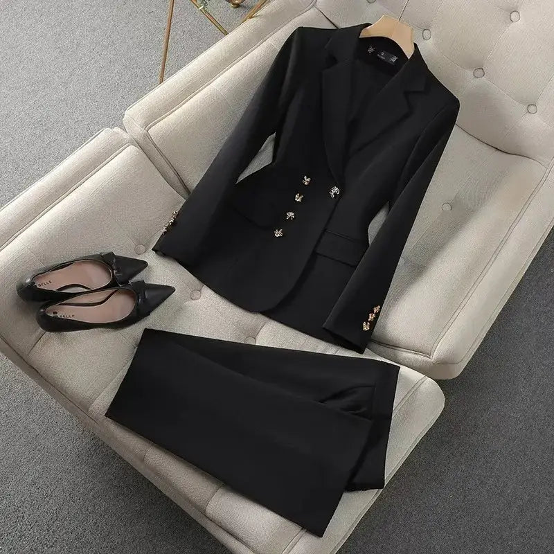 Veste noire à boutons décoratifs argentés et pantalon noir assorti, présentés sur un canapé beige capitonné, dans la collection d’ensemble de tailleur d’affaires pour femme cadre rose.
