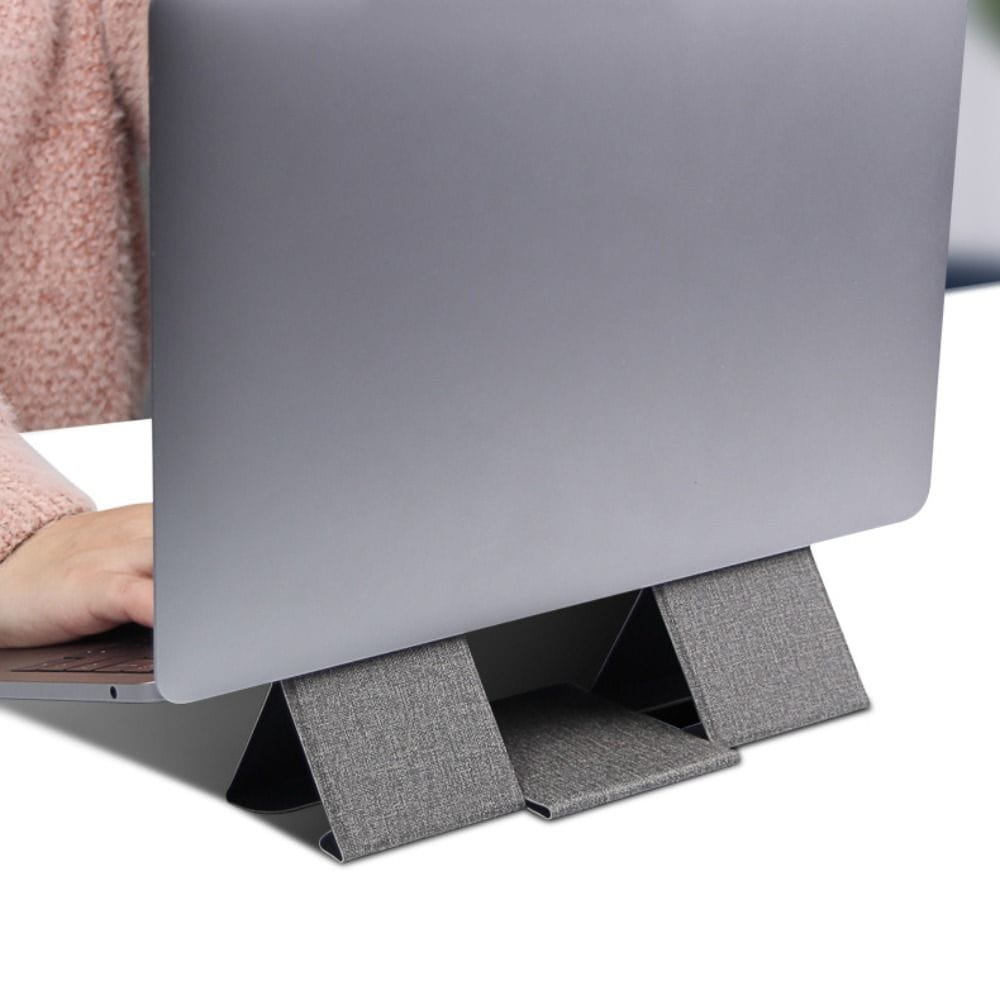 Grauer faltbarer Laptopständer aus strukturiertem Stoff, der einen silbernen Laptop trägt, ausgelegt für 12- bis 16-Zoll-Notebooks.