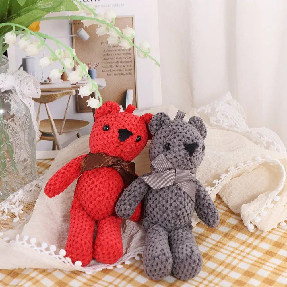 Peluches en forme d’ourson teddy au crochet faites à la main, en laine rouge et grise, avec des nœuds marron et à rayures.