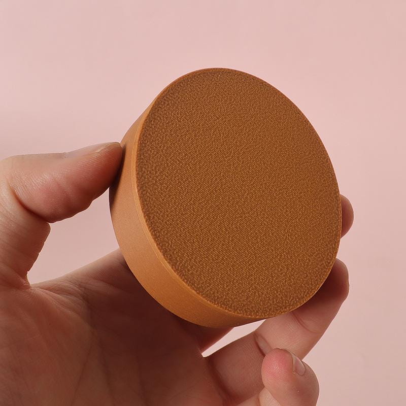 Un petit blender à maquillage rond et de couleur beige, en éponge, à surface texturée, présenté à côté d’une étagère d’exposition miniature en bois pour meuble mural de poupée.