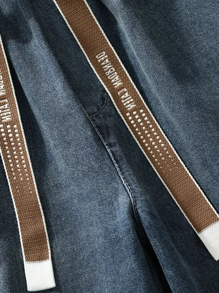 Jean cargo en denim ample pour homme, grande taille, avec un cordon de serrage tissé marron bordé de blanc et un détail d’inscriptions à points.